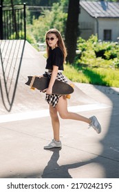 Teenager Skater Girl Holding Skateboard And Standing In The Skaters Park