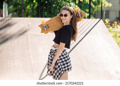 Teenager Skater Girl Holding Skateboard And Standing In The Skaters Park