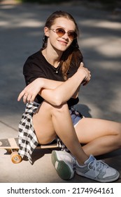 Teenager Skater Girl Is Sitting On Skateboard On The Skaters Park