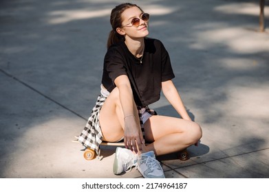 Teenager Skater Girl Is Sitting On Skateboard On The Skaters Park