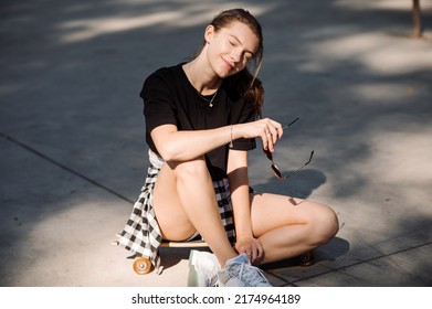 Teenager Skater Girl Is Sitting On Skateboard On The Skaters Park