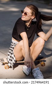 Teenager Skater Girl Is Sitting On Skateboard On The Skaters Park