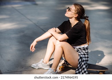 Teenager Skater Girl Is Sitting On Skateboard On The Skaters Park