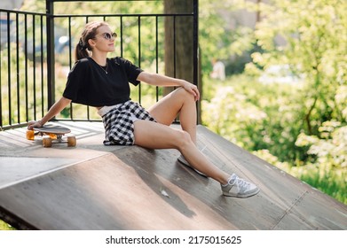 Teenager Skater Girl Is Sitting And Resting On The Ramp In The Skate Park