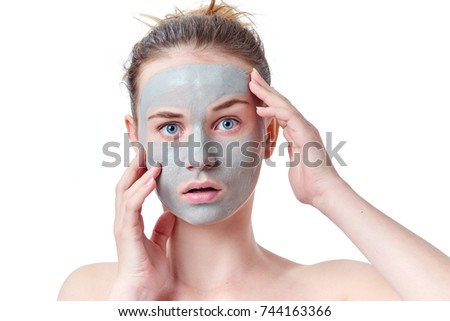 Teenager skincare concept. Young teen girl with dried clay facial mask making funny face, isolated on white background. 