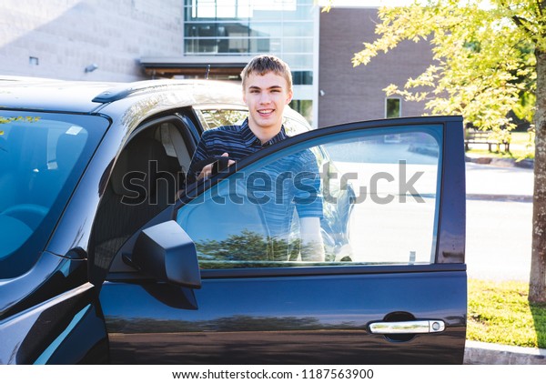Teenager stepping out of his car on the first day\
of school.