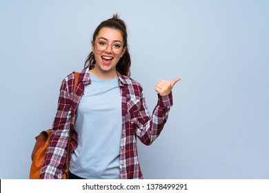 Teenager Student Girl Over Isolated Blue Wall Pointing To The Side To Present A Product