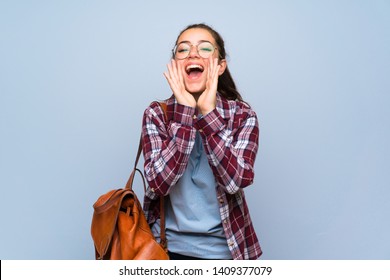 Teenager Student Girl Over Isolated Blue Wall Shouting And Announcing Something