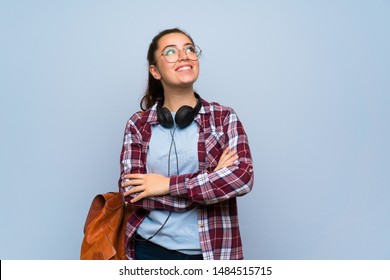 Teenager Student Girl Over Isolated Blue Wall Looking Up While Smiling