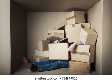 Teenager Student In Small Office Littered With Boxes, Concept - Too Much Work, Male Feet Under A Heap Of Carton Boxes