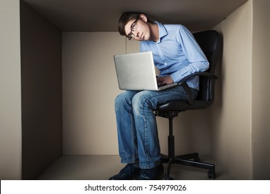teenager, student in small office working on laptop, in an uncomfortable position, not enough space