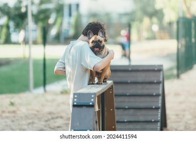 Teenager Teaching His Cute French Puppy Bulldog On Special Playground For Dogs. Boy Learning Commands With Red Bulldog In The Park. Practice With A Dog Outside. Still Life, Friendship With A Puppy	