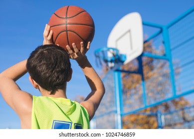 teenager throwing a basketball into the hoop from behind