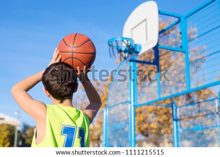 Foto Bild Junger männlicher Teenager spielt Basketball auf einem Platz im Freien.