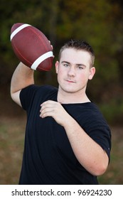 Teenager Throwing A Football Around In The Park.