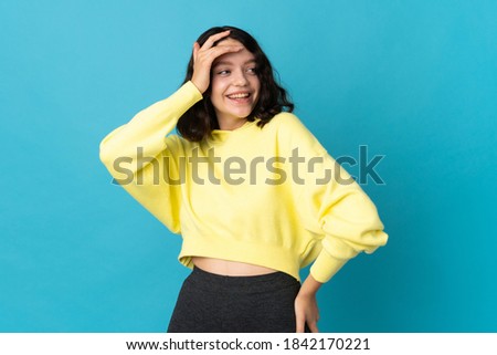 Teenager Ukrainian girl isolated on blue background smiling a lot