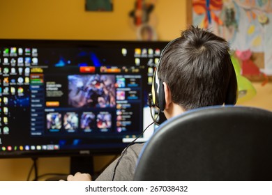 Teenager Using Computer At Home With Headphones, Play Game In His Child Room