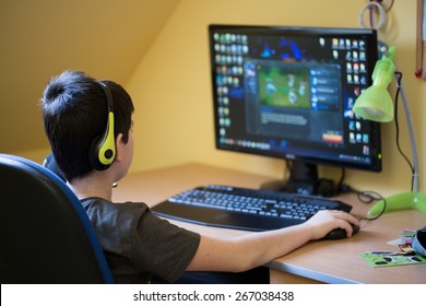 Teenager Using Computer At Home With Headphones, Play Game In His Child Room