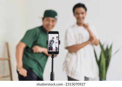 Teenager vlogger boys recording video dances to reel tiktok using smartphone at home. Gen Z talent people play video selfie shoot app for show share viral story. 