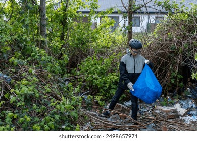 Teenager volunteer wearing a helmet up trash in the park with a blue bag. Concept of environmental conservation, community service and active recreation. High quality photo - Powered by Shutterstock