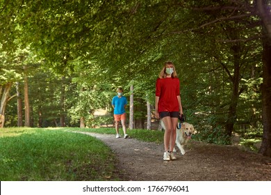 A Teenager Is Walking Her Dog, Followed By An Older Woman. Face Mask. Distance.