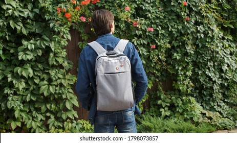 A Teenager, Wearing A Denim Jacket And A Rucksack With Communist Pins Among The Vine In Summer.