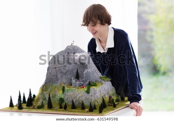 Teenager working on model building school project.\
Kids build miniature scale model mountain for geography class in\
high school. Extracurricular activities and hobby club. Art and\
crafts for child.