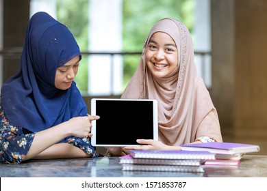 Teenager Young Adult Asian Thai Muslim university college students holding digital tablet and pile of books using for education and online education concept - Powered by Shutterstock