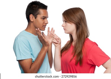 Teenagers in argument. Girl accusing. Boy defending. Studio shot. White background.