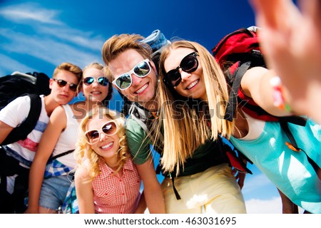 Teenagers with backpacks taking selfie, summer festival