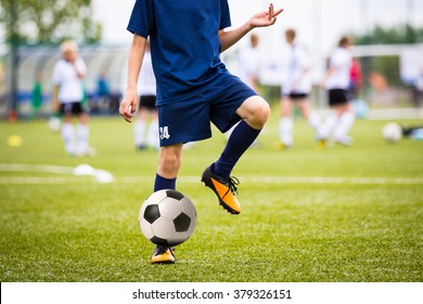 Teenagers Boys Playing Soccer Football Match. Young Football Players Running And Kicking Soccer Ball On A Soccer Pitch.