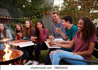 Teenagers at a fire pit eating take-away pizzas, close up