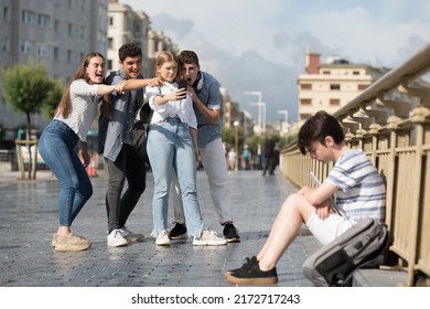 Teenagers Group Laughing And Recording Sad Friend. Bullying And Cyberbullying Concept.