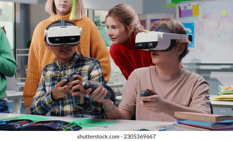 Teenagers looking at classmates in vr headset and joystick playing game in classroom. Children use virtual reality goggles at school - Powered by Shutterstock