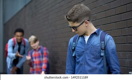 Teenagers mocking boy in eyeglasses, spreading malicious rumors, verbal bullying