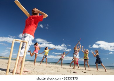 Teenagers Playing Cricket On Beach