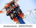 Teenagers ride head down on a carousel. Extreme rides in the park.