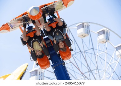 Teenagers ride head down on a carousel. Extreme rides in the park.