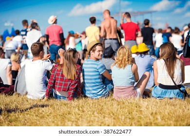 Teenagers at summer music festival, sitting on the grass - Shutterstock ID 387622477