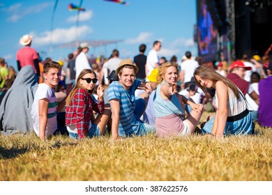 Teenagers, summer music festival, sitting in front of stage - Shutterstock ID 387622576