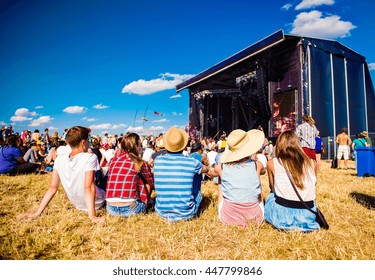 Teenagers, summer music festival, sitting in front of stage