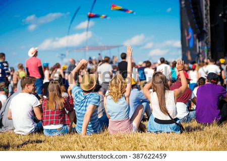 Teenagers, summer music festival, sitting in front of stage