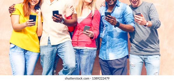 Teenagers texting mobile phone messages row on pink background - Multiracial friends holding smartphone smiling - Multicultural teens generation using cellphone - Modern communication concept - Image