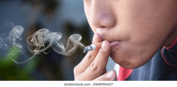 Teenagers underage smoking a cigarette causes bad habits causing addiction. Asian schooboy smoking problems, feeling sad, unhappy and depression, stressed in an old dirty grungy place. - Powered by Shutterstock