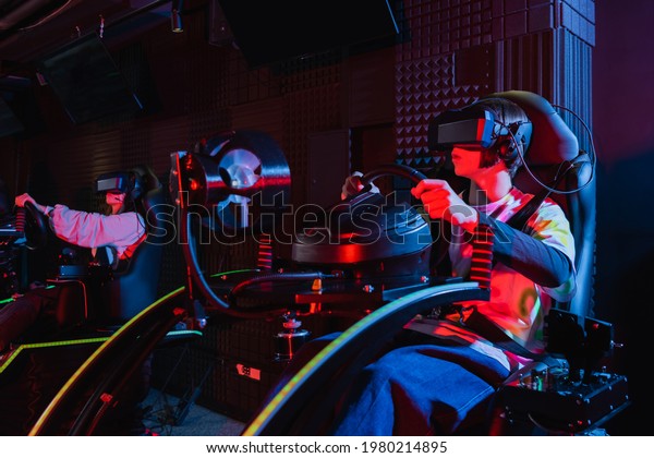 teenagers in vr headsets racing on car simulators in
game zone
