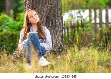 Teengirl writing in a notebook while sitting in the park