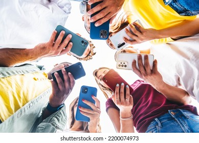 Teens in circle holding smart mobile phones - Multicultural young people using cellphones outside - Teenagers addicted to new technology concept - Powered by Shutterstock