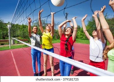 Teens Playing Actively Near The Volleyball Net