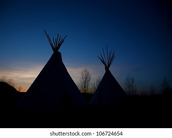 Tee-pees among Birch Trees silhouetted against vignetted blue sky at nightfall - Powered by Shutterstock