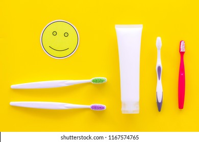 Teeth Care, Dental Care. Toothbrushes And Tooth Paste Near Smile Face Emoji On Yellow Background Top View